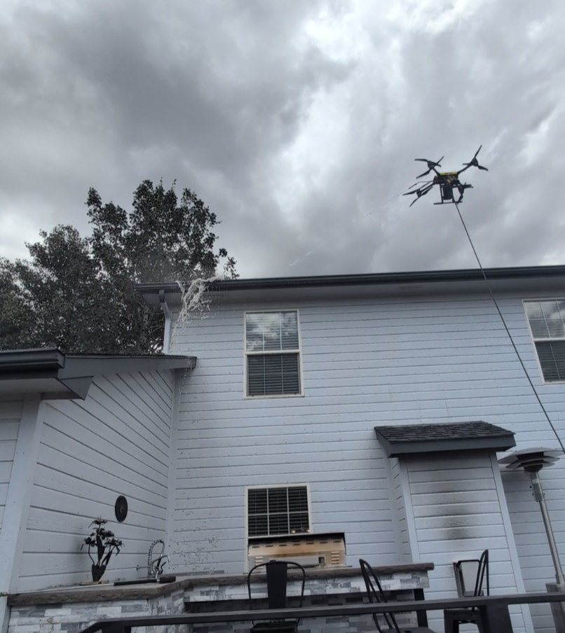 Drone cleaning gutters above a home